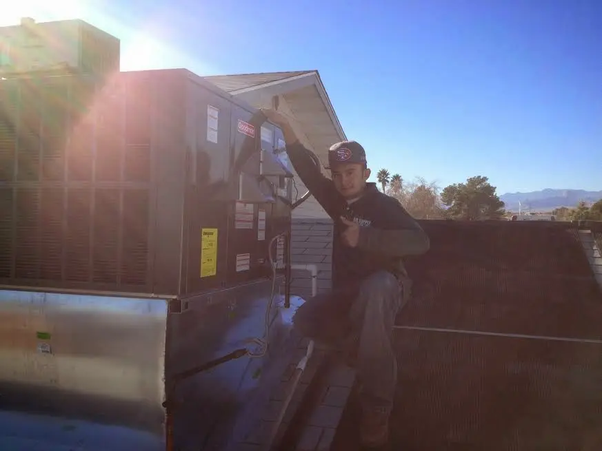 HVAC technician performing Air Duct Cleaning on a rooftop unit in Attica